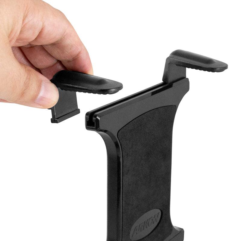 A hand adjusts the top clamp of a black Slim-Grip® Universal Tablet Holder w/ Dual-T mounting pattern, preparing to securely place a device in this versatile holder.