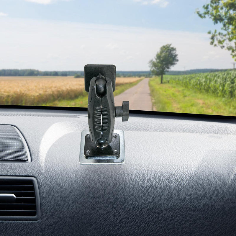 A Square Mounting Backer Plate with a 4-hole AMPS drill-base pattern secures a phone or GPS on the car dashboard. Through the windshield, a rural road, open fields, and a lone tree are visible under a partly cloudy sky.