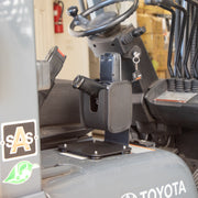 The SteadyMag™ Magnetic Mount System with Universal Barcode Scanner Holder is installed on a stand inside the Toyota forklift cabin, next to the driver’s seat and steering wheel, keeping keys and controls easily accessible.