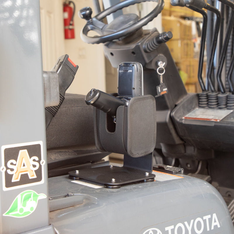 The SteadyMag™ Magnetic Mount System with Universal Barcode Scanner Holder is installed on a stand inside the Toyota forklift cabin, next to the driver’s seat and steering wheel, keeping keys and controls easily accessible.