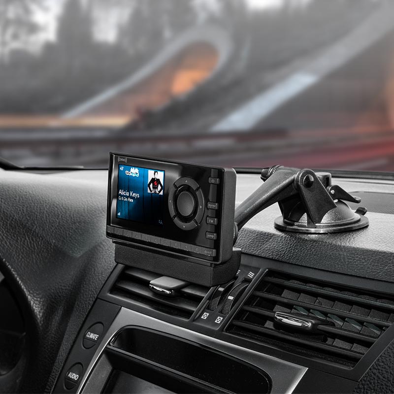A Sticky Suction Windshield or Dash Car Mount for XM and Sirius Satellite Radio is attached by the car’s air vents, securely displaying Alicia Keys Girl on Fire on the satellite radio receiver.