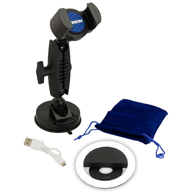 The Suction RoadVise® Phone Mount and Ring Light Bundle, featuring a phone mount, USB charging cable, LED ring light, and blue velvet drawstring pouch, is displayed on a white background—ideal for beauty content creation.