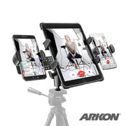 The TW Broadcaster TriStreamer Tripod Adapter for Slim-Grip® Tablet and Dual RoadVise® Phone holds a tablet and two smartphones—all showing a woman in a studio—for dual live streaming. ARKON logo is at the bottom right.
