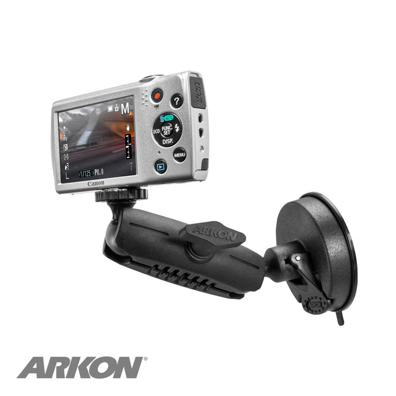 A digital camera is attached to the Windshield Suction Camera Mount, which is black and features a 1/4-20 camera mounting pattern. The camera’s screen shows an image, and the Arkon logo appears in the bottom left corner.