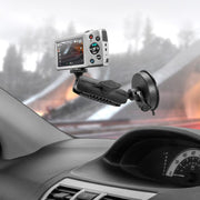 A compact camera with a 1/4-20 mount is attached to a car dashboard using the Windshield Suction Camera Mount, display screen on and capturing the blurred road view through the windshield.