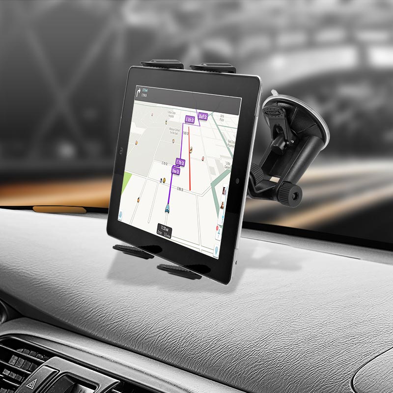 A Windshield Suction Slim-Grip® Tablet Mount holds a tablet on the dashboard, displaying a navigation map while the blurred road can be seen through the windshield in the background.