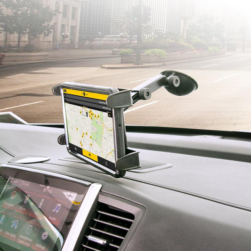A GPS tablet secured with the Windshield Suction Tablet Mount with Extension Arm displays a city map and directions. Sunlight streams through the windshield, revealing city buildings outside.